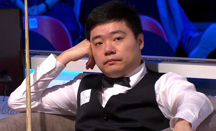 杨华明坐在不远处的一把有靠背的凳子上，凳子前方还摆着一把小马扎，绑着夹板的脚架在上面。